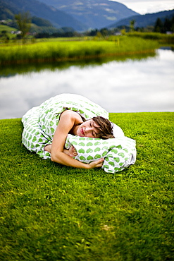 Woman lying with bedding on a golf course, Styria, Austria