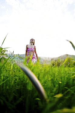 Young woman walking through high grass, Riegersburg, Styria, Austria