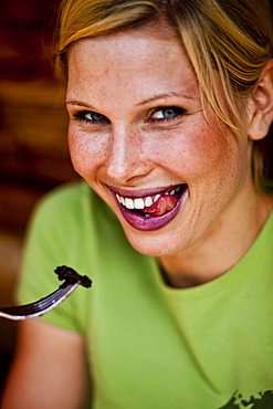 Young woman eating pancake with blueberries, lake Duisitzkar, Styria, Austria