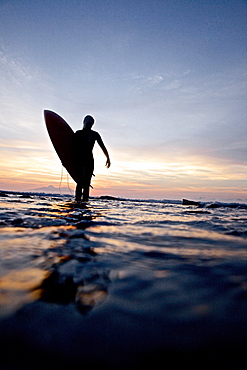 Female surfer carrying surfboard, Praia, Santiago, Cape Verde