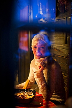 Smiling young woman looking through a window