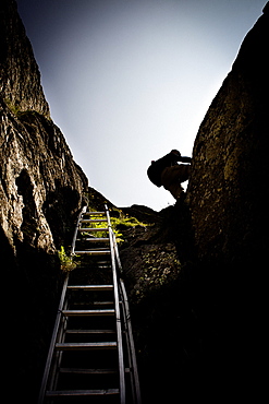 Hiker scalling a rocky step, on the way to Schreckhorn hut, Lower Grindelwald glacier, Bernese Oberland, Switzerland