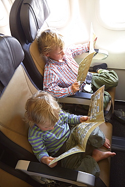 Two boys reading safety instructions in an airplane, Munich, Bavaria, Germany