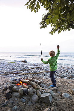 5 years old boy dancing around the campfire, childhood, adventure, outdoor, holiday, Baltic sea, MR, Bornholm, near Gudhjem, Denmark, Europe