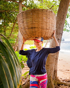 Young woman trying to carry a big basket on her head, Sao Tome, Sao Tome and Principe, Africa