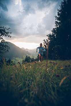 Young woman runs in the evening mood at Falkenstein, Allgäu, Bavaria, Germany