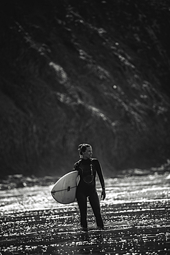 Surfer stands with surfboard on the beach, surfing, vacation, Portugal