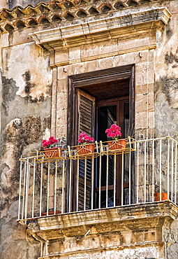 Facade of a residential building with balcony and blossoming plants, Syracuse, Sicily, Ortigia, Italy