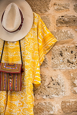 Clothes and accessories hanging on display against a stone wall, Alcudia, Mallorca, Balearic Islands, Spain