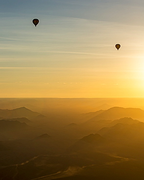 Silhouette of hot air balloons in the golden sky over the sand dunes at sunrise in the Namib Desert, Sossusvlei, Hardap Region, Namibia