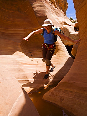 Female athlete navigating a slot canyon water feature, Hanksville, Utah, United States of America