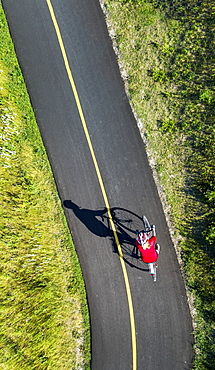 View from directly above a cyclist in a red shirt on a paved cycling trail, Calgary, Alberta, Canada