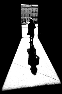 Silhouette and shadow of a woman going through a doorway to a town square towards City Hall, Arles, Provence Alpes Cote D'Azur, France