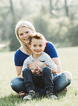 Portrait of mother with young son sitting on the grass in a park, Edmonton, Alberta, Canada