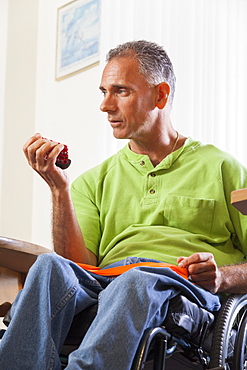 Man with spinal cord injury in a wheelchair using hand strengthening equipment