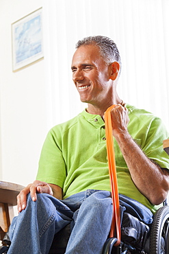 Man with spinal cord injury in a wheelchair using hand and arm strengthening equipment