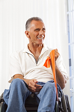 Man with spinal cord injury in a wheelchair using hand and arm strengthening equipment