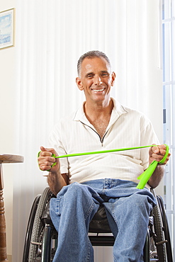 Man with spinal cord injury in a wheelchair using hand and arm strengthening equipment