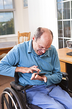 Man with Friedreich's Ataxia in wheelchair using a smartphone with deformed hands