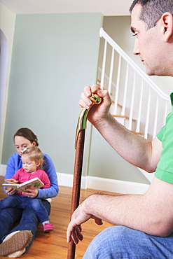 Man after anterior cruciate ligament (ACL) surgery with wife and daughter at home