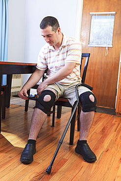 Man adjusting braces on his knees after anterior cruciate ligament (ACL) surgery