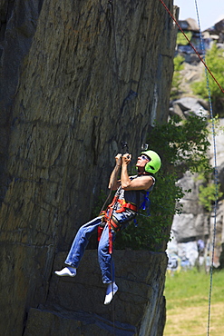 Man with spinal cord injury using adaptive climbing equipment for rock climbing