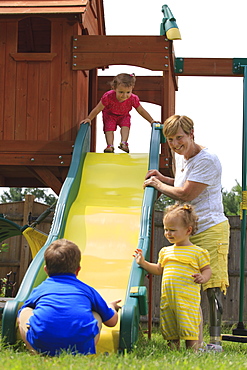 Grandmother with a prosthetic leg playing on a slide with her grandchildren