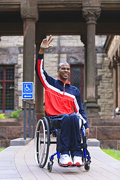 Man in wheelchair who had Spinal Meningitis using a ramp and waving