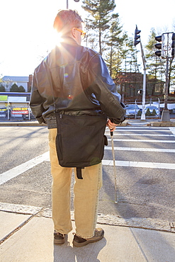 Man with congenital blindness about to cross the street using his cane