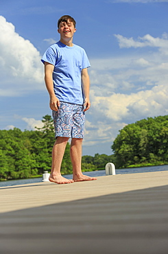 Happy young man with Down Syndrome standing on a dock