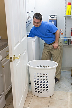 Man with Down Syndrome taking out dry clothes from washing machine