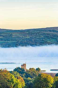 Castlebawn Tower house on the banks of Lough Derg surrounded in fog on an autumn morning; Clare, Ireland