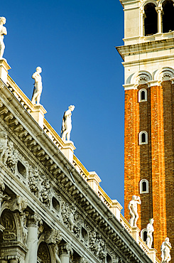 Detail of clock tower and statues along a roofline; Venice, Veneto, Italy