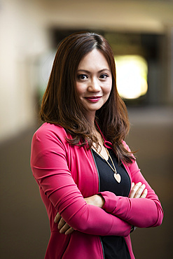 A close-up portrait of an Asian business woman in a hallway at her place of work: Edmonton, Alberta, Canada