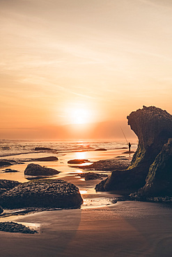 Sunset at Parangendog Beach with a person fishing from the beach; Purwosari, Yogyakarta, Indonesia