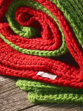 Close-up of a red and green knitted garments folded together and laying on a wooden table; Studio