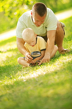 Father And Son Looking Through Magnifying Glass