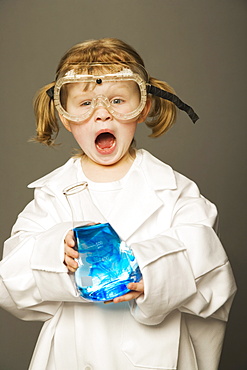 Little Girl With Safety Goggles And Lab Coat Holding A Science Beaker