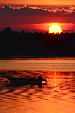 A silhouetted boat at sunset at Cote a Fabien., Cote a Fabien, Kouchibouguac National Park, Kouchibouguac, New Brunswick, Canada.