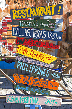 Close-up of colorful mileage signs for multiple locations at a restaurant on Grand Cayman in the Cayman Islands, Grand Cayman, Cayman Islands, Caribbean