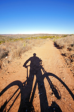 Shadow of a cyclist and bike on a dirt path in a vast open landscape in Caprock Canyons State Park and Trailways, Texas, USA, Texas, United States of America