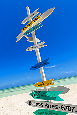 Signpost on a tropical white sand beach showing distance to countries around the world from Cuba in the Caribbean Sea, Cayo Guillermo, Cuba