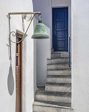 Bell mounted above the doorway on a whitewash building in Greece, Ano Mera, South Aegean, Greece