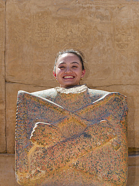 Girl posing as ancient Egyptian god with headless statue at the Karnak Temple in Luxor, Egypt, Luxor, Egypt