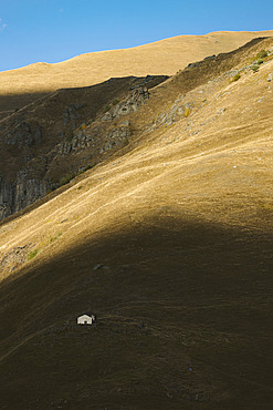 Lone house in the shadows on a vast mountainside along Trusco Gorge, Kvemo Okrokana, Georgia