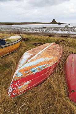 Old brightly painted fishing boats and Lindisfarne Castle in winter, Holy Island, Northumberland, England, United Kingdom, Europe