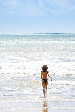 A young woman running into the tropical Atlantic, Morro de Sao Paulo island, Bahia, Brazil, South America