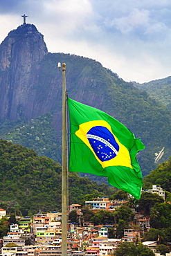 Brazilian flag with a favela and the Christ statue on Corcovado peak in the background, Rio de Janeiro, Brazil, South America