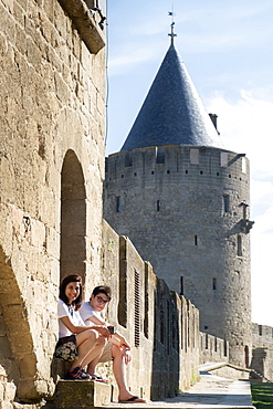 A mother and son on holiday and seated outside the main wall of the medieval castle, Carcassonne, UNESCO World Heritage Site, Aude, Languedoc, France, Europe