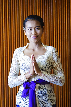 A Balinese woman wearing traditional busana adat temple clothes comprising a white kebaya blouse, a sash and a batik sarong, Bali, Indonesia, Southeast Asia, Asia